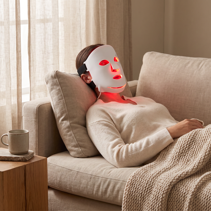 Omnitality Lumora Red Light Face Mask being used while relaxing on a couch at home